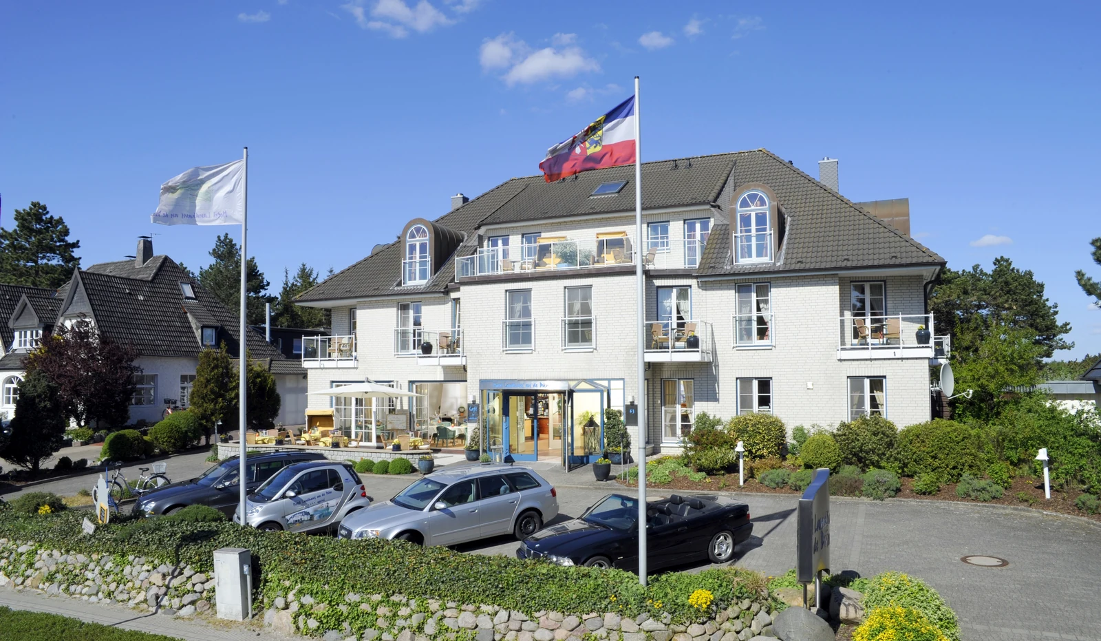 Weiße Fassade des Landhaus an de Dün mit Balkonen und Eingang unter blauem Himmel